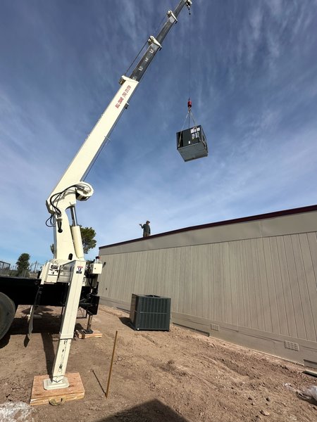 Crane lifting a packaged HVAC unit up to the roof of a modular building