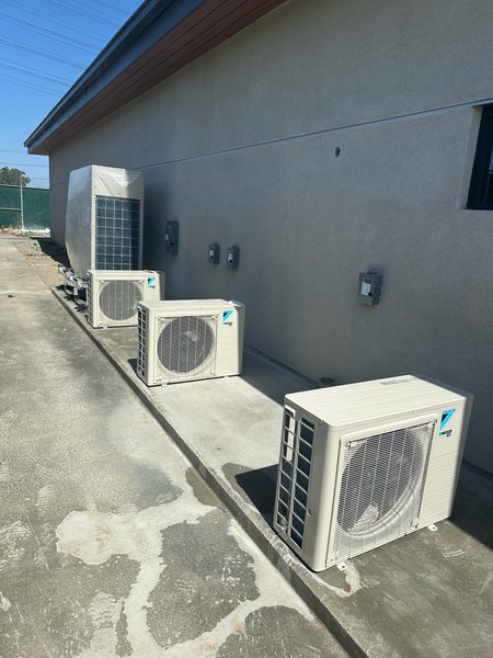 Row of Daikin outdoor condensing units and a VRV unit installed along the wall of a modular building