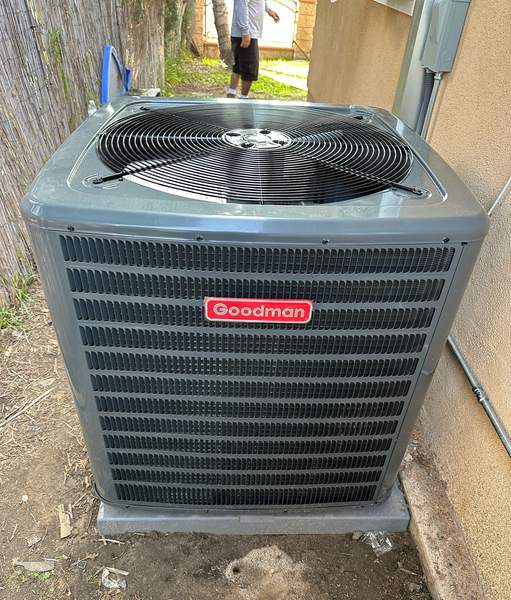 New Goodman split-system condensing unit set on a pad beside a home