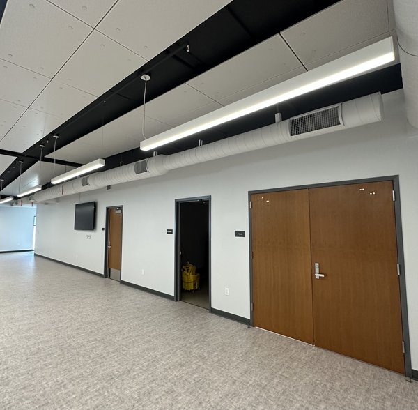 Interior corridor with exposed white spiral supply duct and linear supply grilles